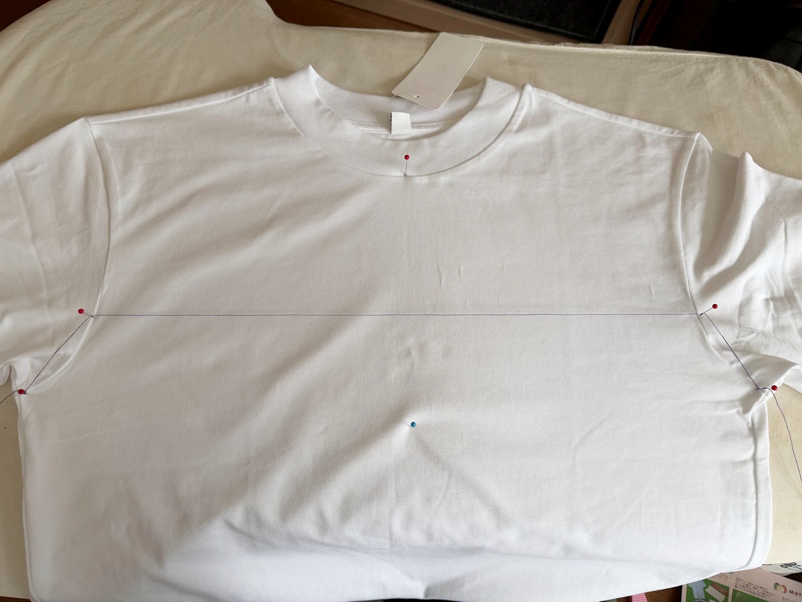 まち針と糸でロゴの位置を決めた白いTシャツ