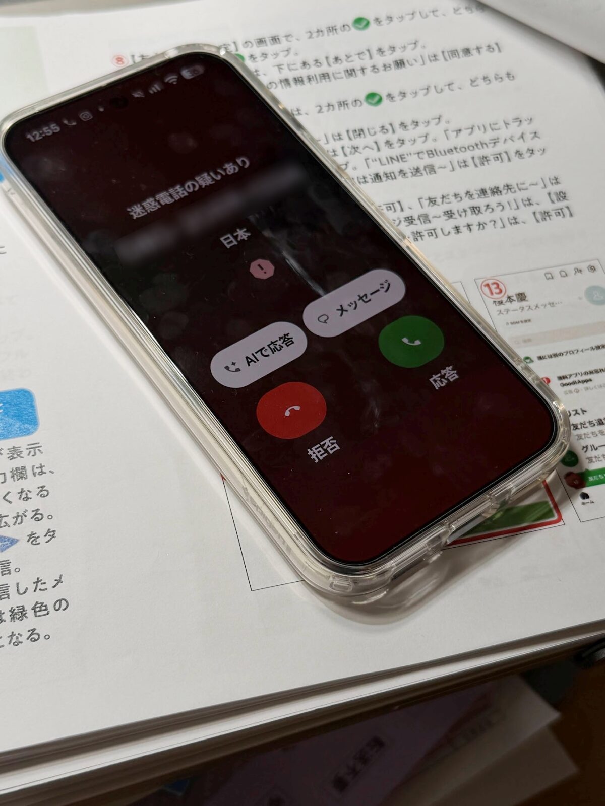 机の書類の上の iPhone に着信が入っている様子