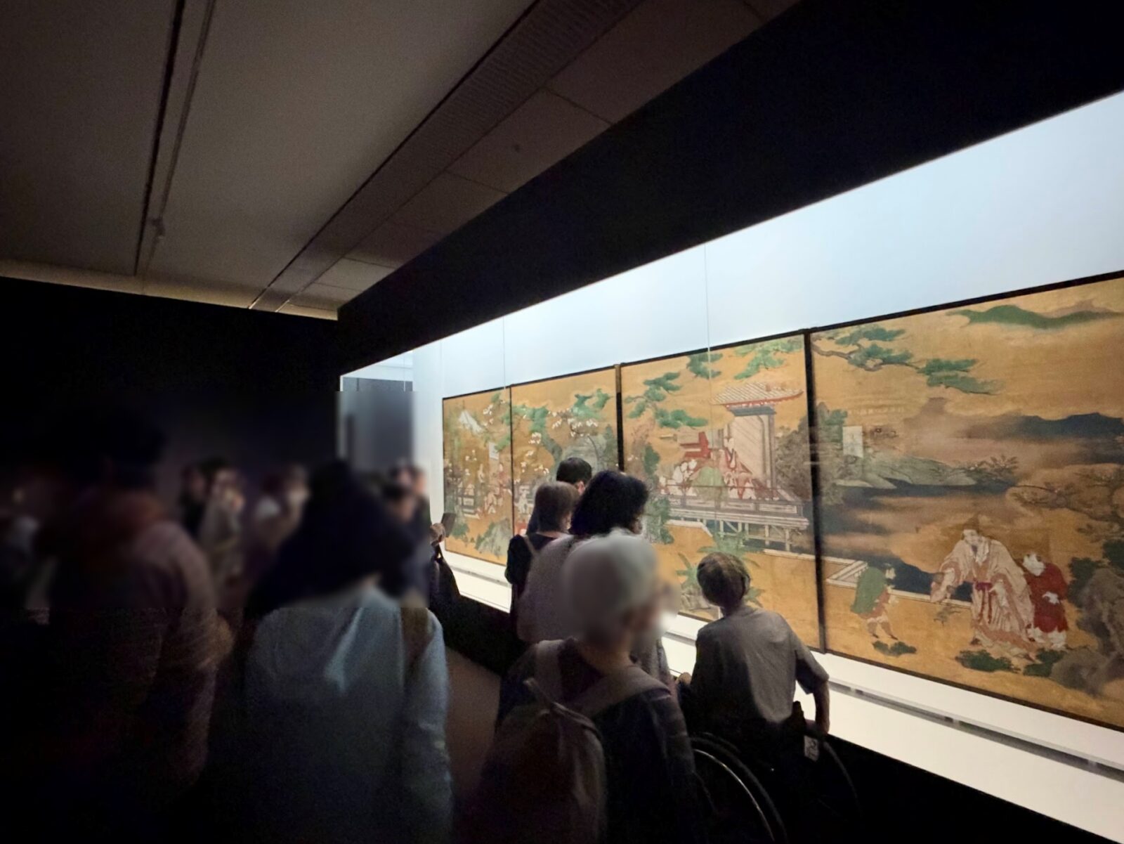 人物や楼閣が描かれた金地の襖絵と、見入る来場者